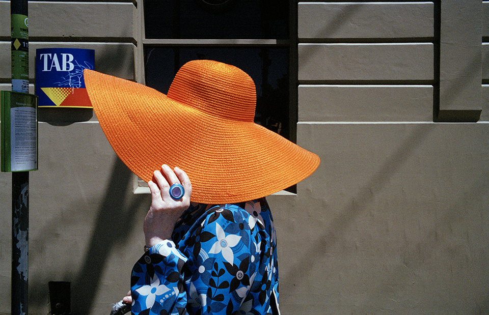 Eine Frau hat einen leuchtend orangenen Hut auf. Melbourne, Straßenfotografie von Jesse Marlow.