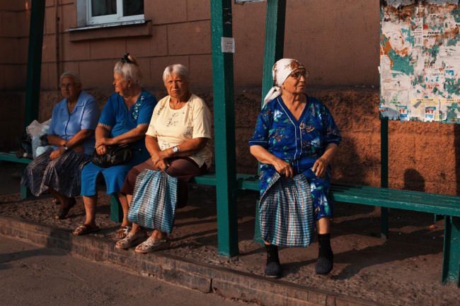 Vier Frauen mit grauen Haaren warten auf den Bus.