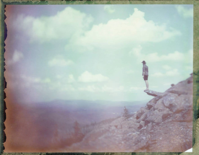 Ein Mann steht auf einem Felsvorsprung und schaut in die Weite.