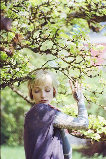 Blonde Frau in einem Magnolienbaum.