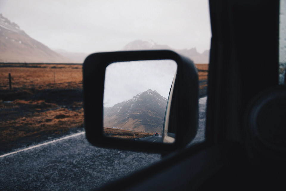 Vernebelte Berge im Rückspiegel eines Autos. 