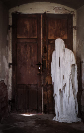 Ein Geist aus Gips steht vor einer hölzernen Tür