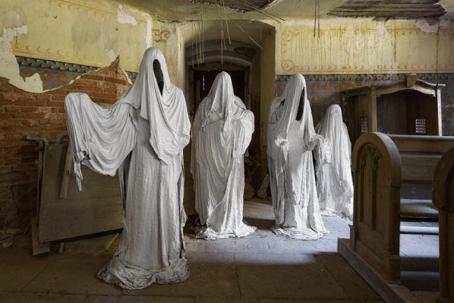 Vier stehende Geister vor einem Eingang.