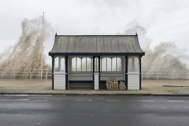 Eine Bushaltestelle bei Wales, die am Meer liegt und Wellen heraufschlagen. 