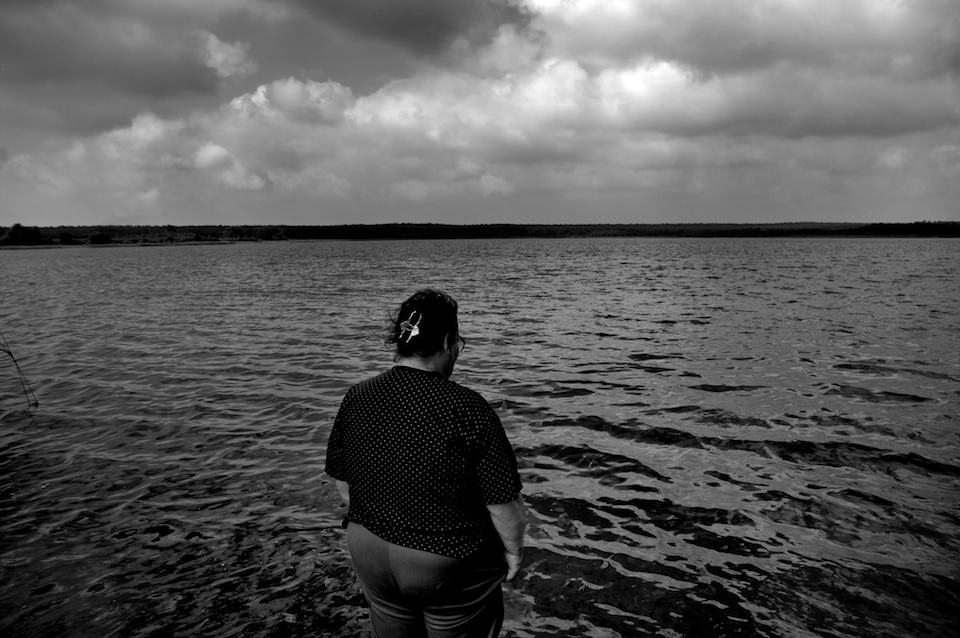 Straßenfotografie: Eine Frau steht am Wasser. Düstere Aufnahme. 
