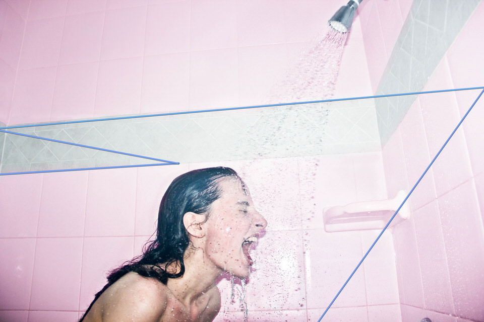 Eine Frau unter der Dusche, sie lacht. 