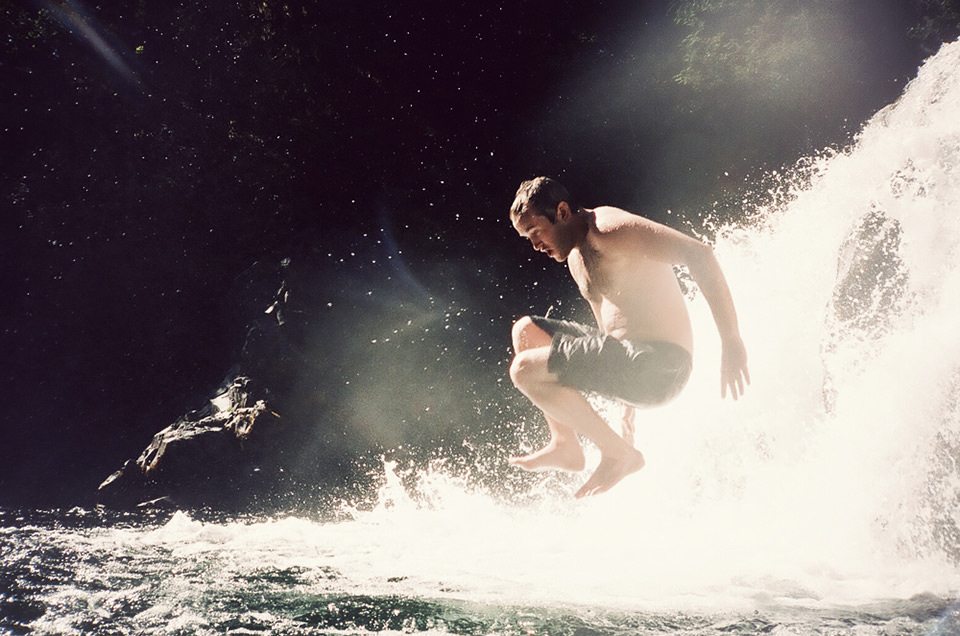 Ein Mann springt von einem Wasserfall ins Wasser.
