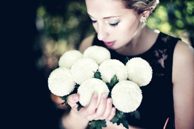Eine Frau hält einen Straus weißer, ballförmiger Blumen.