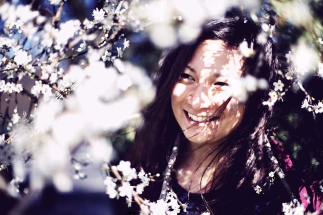 Eine lachende Frau zwischen vielen weißen Blüten.
