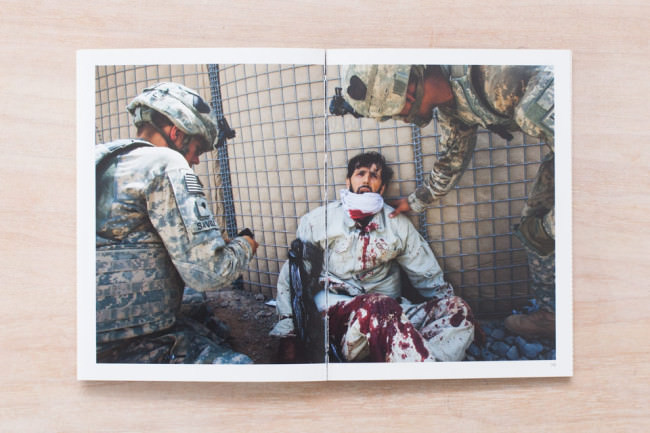 Ein verletzter Soldat wird von zwei anderen Soldaten begutachtet. 
