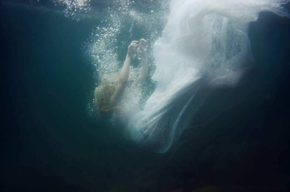Unterwasserfoto einer fallenden Frau in weißem Kleid
