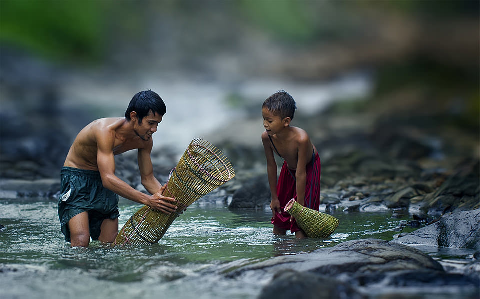 Ein Mann und ein Junge stehen mit Korbgeflechten im Wasser.