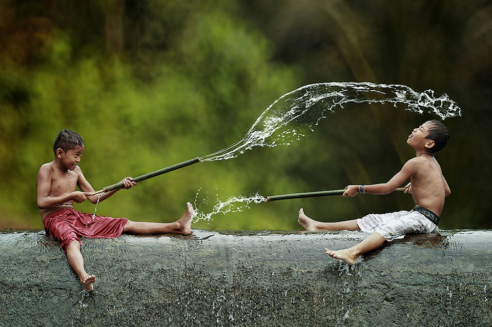 Zwei Jungen spritzen sich mit Wasserpistolen gegenseitig nass.