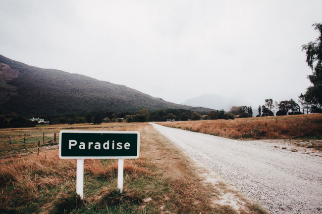 Straße in einer Berglandschaft mit Schild „Paradise“