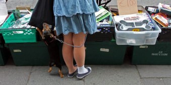 Ein Hund steht mit seiner Besitzerin an einem Flohmarktstand.
