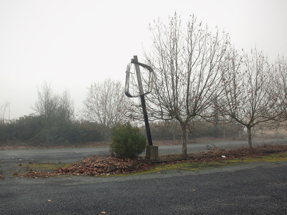 Das Skelett eines Schildes auf einer Straßeninsel vor dichtem Nebel.