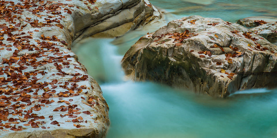 Natur-Fotografie: Wasser schlängelt sich an Steinen vorbei.