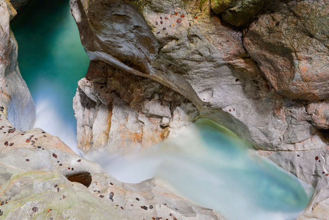 Landschaftsfotografie: Wasser schlängelt sich an verschiedenen Steinen vorbei. 