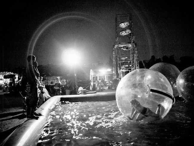 In einem Freizeitpark sind Menschen in Plastikblasen auf einem Pool