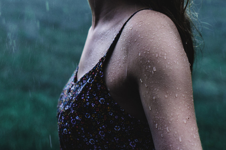 Man sieht den Oberkörper einer Frau im Regen.