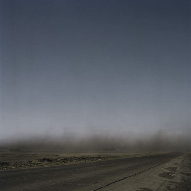 Eine Kohlestaubwolke schwebt über einer Straße durch die mongolische Steppe.