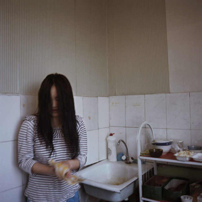 Eine junge Frau steht vor einem Spülbecken und trocknet sich die Hände ab.