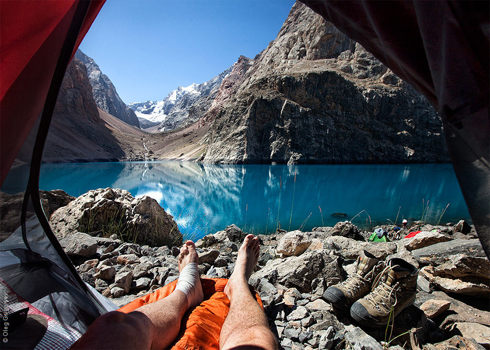 Blick aus einem Zelt heraus auf einen See und Berge.