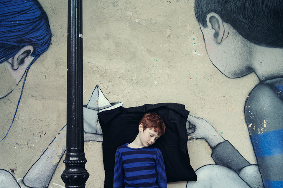 Ein rothaariger schlafender Junge lehnt an einer bemalten Wand