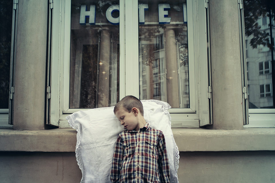 Ein schlafender Junge lehnt vor einem Hotelfenster