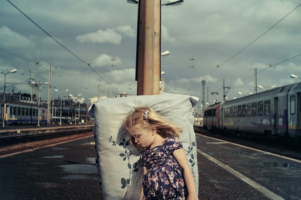 Ein schlafendes Mädchen lehnt an einem Bahnsteig
