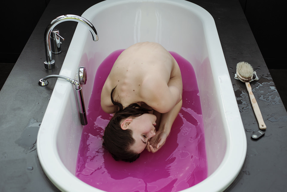 Mädchen in Badewanne mit pinker Flüssigkeit