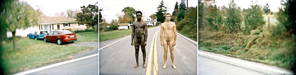 Zwei nackte und beschriftete Männer stehen auf einer Straße.