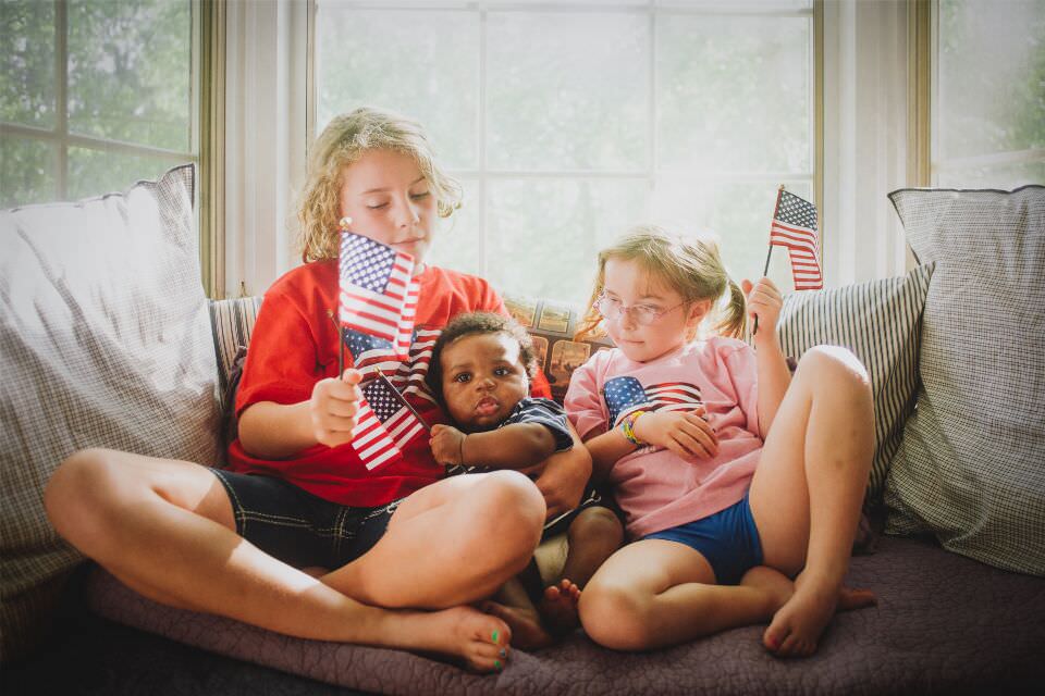 Drei Kinder mit amerikanischen Flaggen in der Hand.