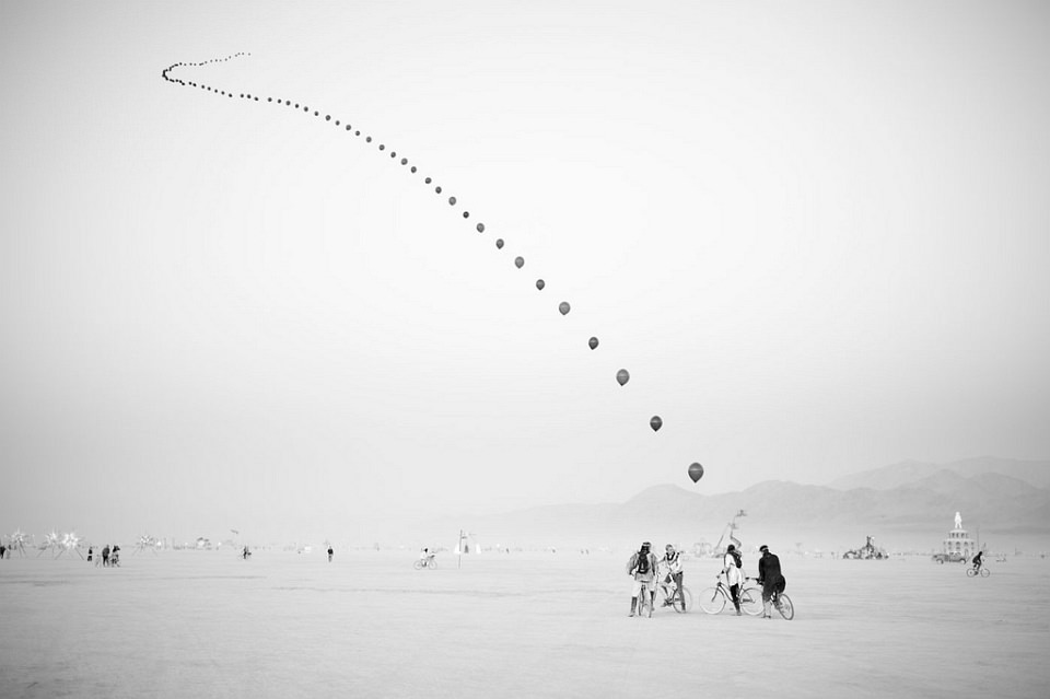 Aneinandergereihte Luftballons über der Wüste.