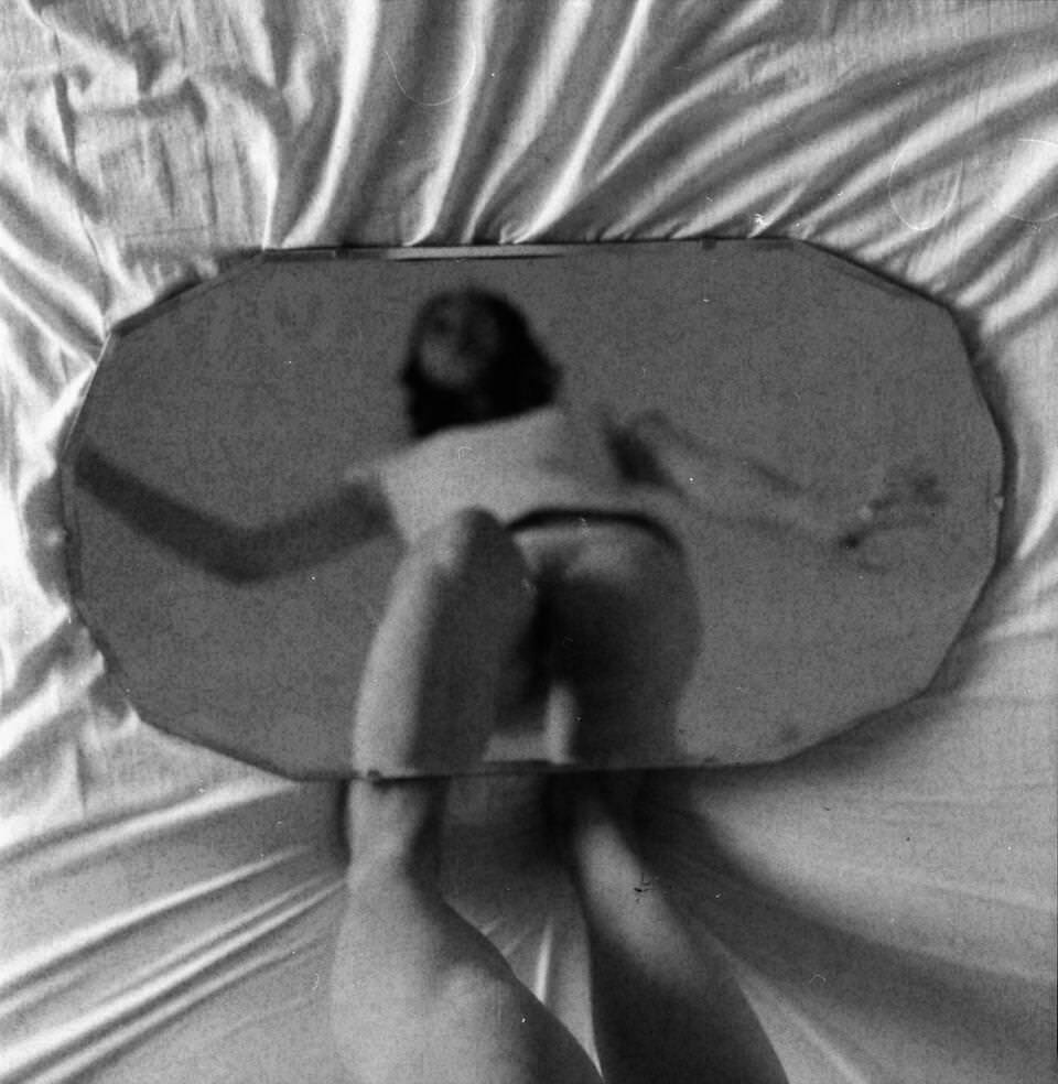 Frau steht über einem runden Spiegel.