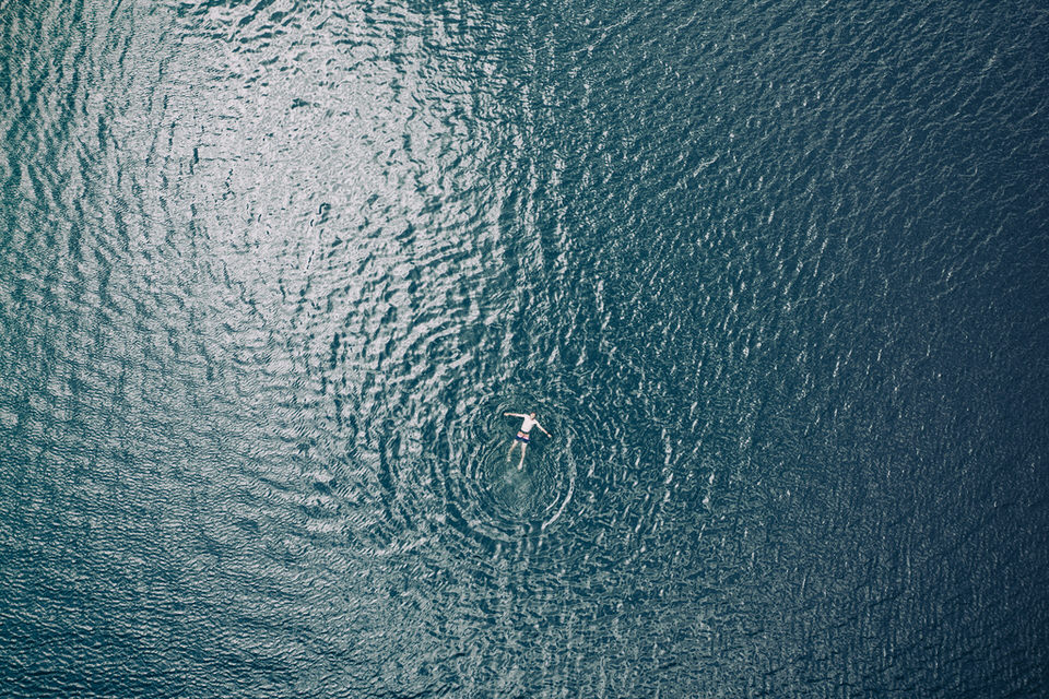Mann schwimmt im Wasser. Perspektive von oben.