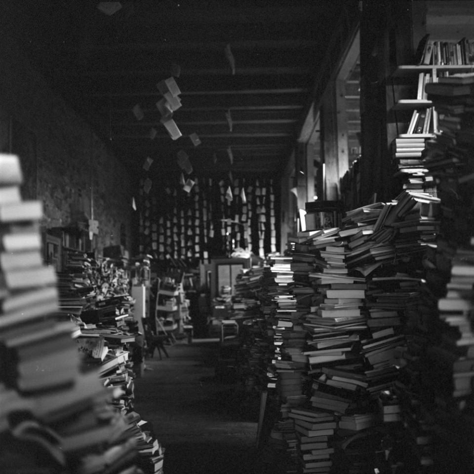 Blick in einen langen Raum voller Bücherstapel.