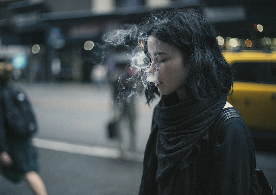 Eine Frau auf der Straße mit Rauch vor dem Mund.