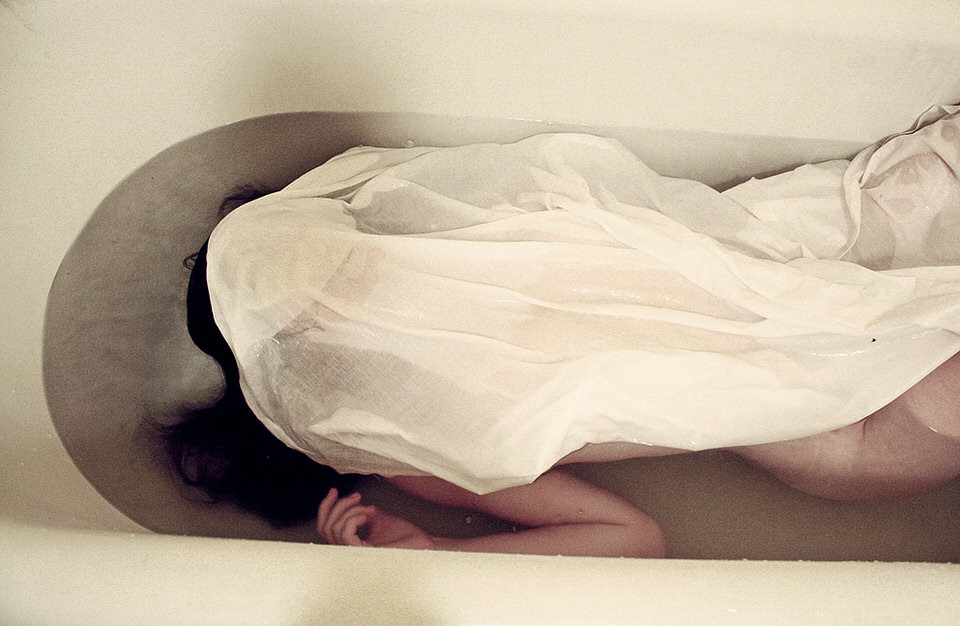 Frau in der Badewanne von einem Tuch bedeckt.