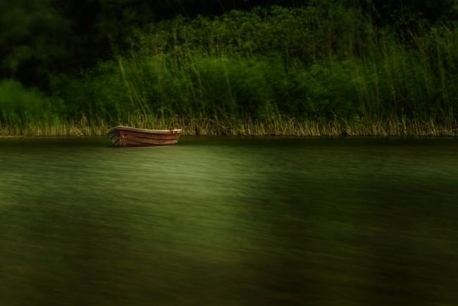 Langzeitbelichtung eines Bootes, das am Ufer eines Sees liegt.