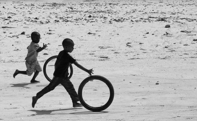 Zwei Jungen spielen mit zwei Reifen am Strand.
