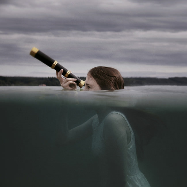 Eine Frau schaut mit einem Fernglas aus dem Wasser