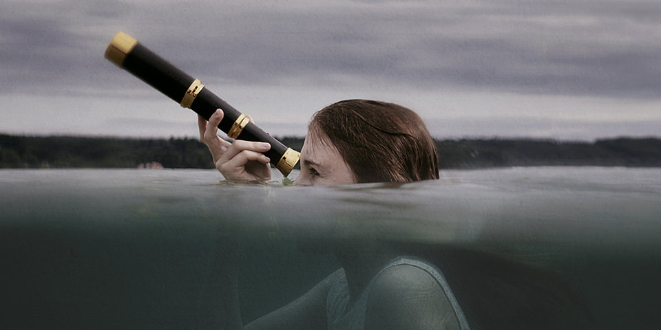 Ein Mädchen durchbricht die Wasseroberfläche mit ihrem Fernrohr.