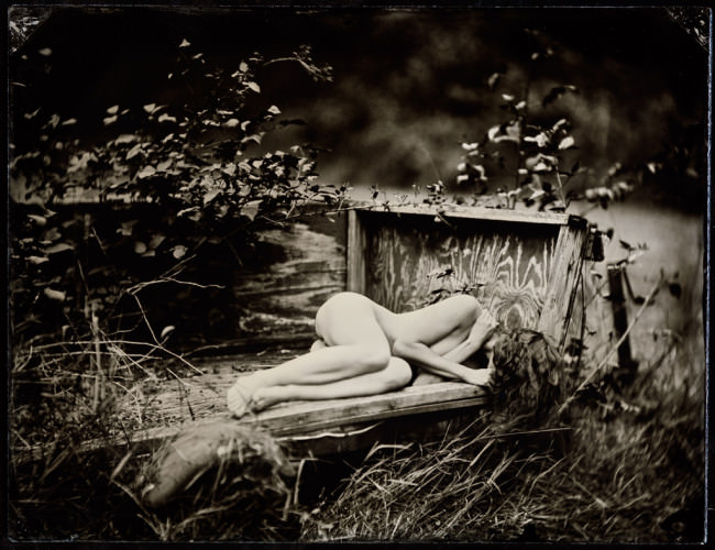 Eine nackte Frau in einem Bett, mitten in der Natur.