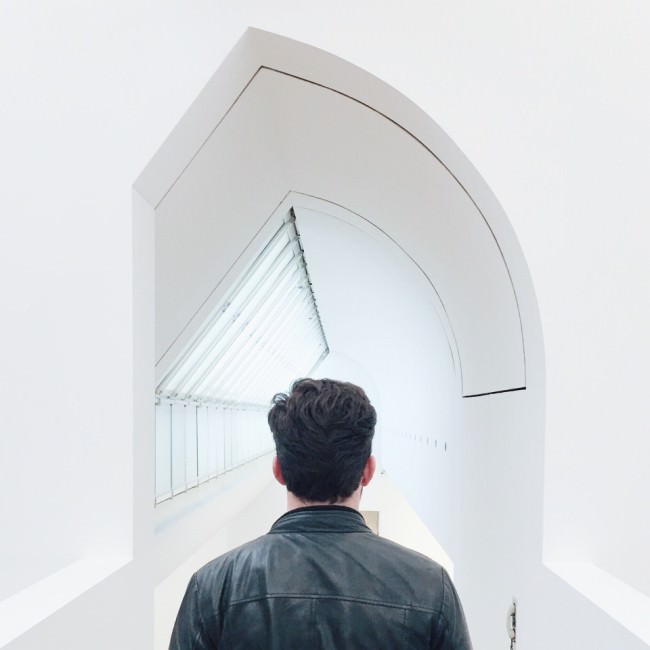 Ein Mann vor einem weißen, langen Korridor mit ungewöhnlicher Form.