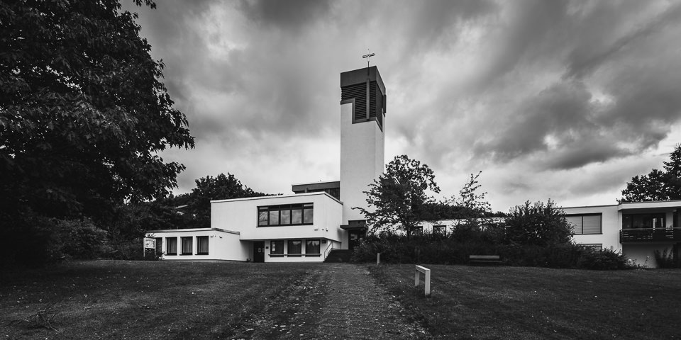 Moderne Kirche vor düsterer Wolkenfront