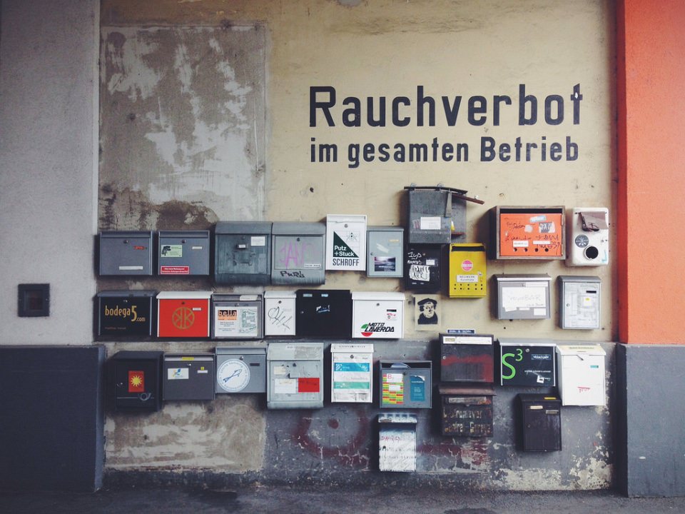 Eine Wand mit sehr vielen unterschiedlichen Briefkästen und dem Schriftzug „Rauchverbot im gesamten Betrieb“.