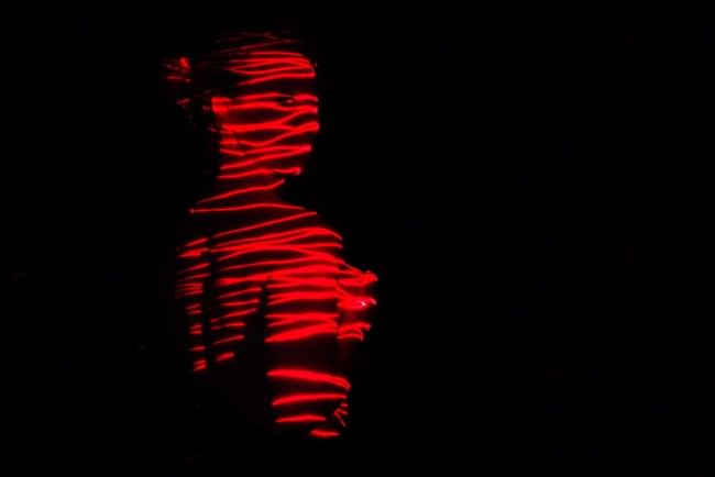 Eine Frau mit roten Lichtstreifen im Dunkeln.