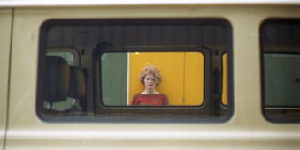 Eine blonde Frau ist durch ein Autofenster sichtbar.