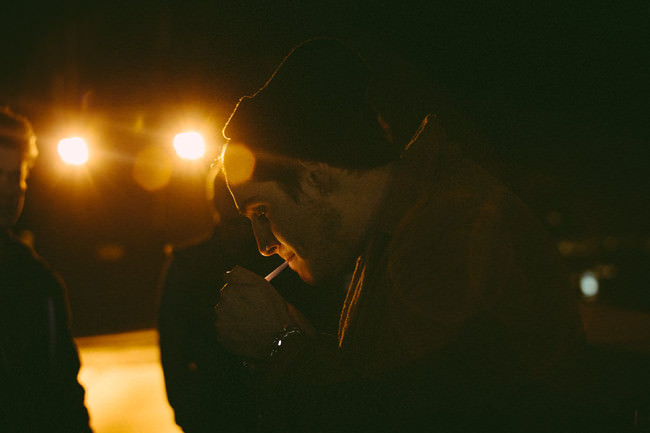 Ein Mann mit Mütze zündet sich im Dunkeln eine Zigarette an.